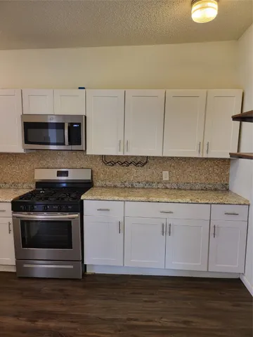 a kitchen with granite countertop a stove and a microwave
