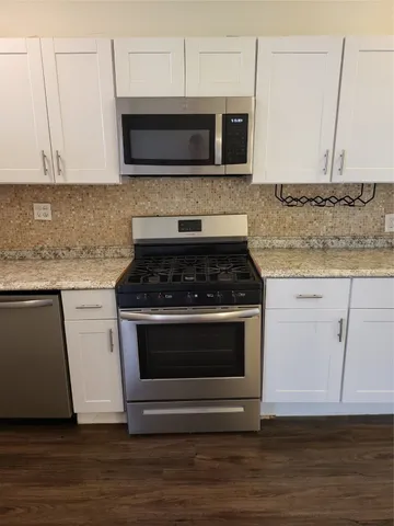 a kitchen with granite countertop a stove and a microwave