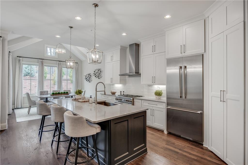 3440 Commander Cove Suwanee, GA 30024 - Photo 18 of 59 a kitchen with stainless steel appliances granite countertop a stove top oven a sink dishwasher a dining table and chairs with wooden floor