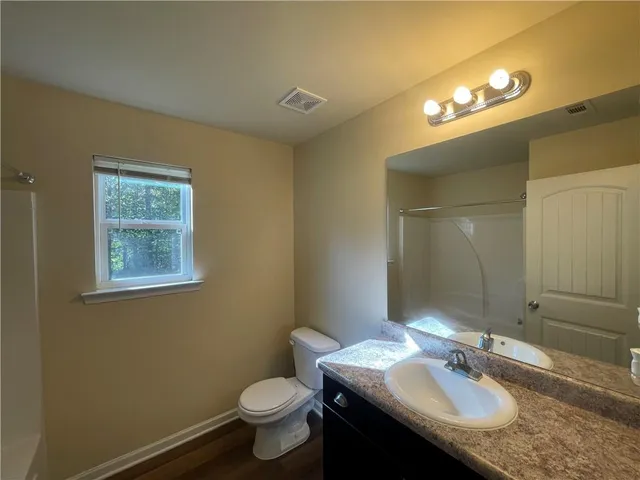 a bathroom with a granite countertop sink toilet and a mirror