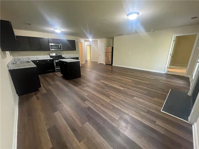 a kitchen with stainless steel appliances wooden floors and view living room