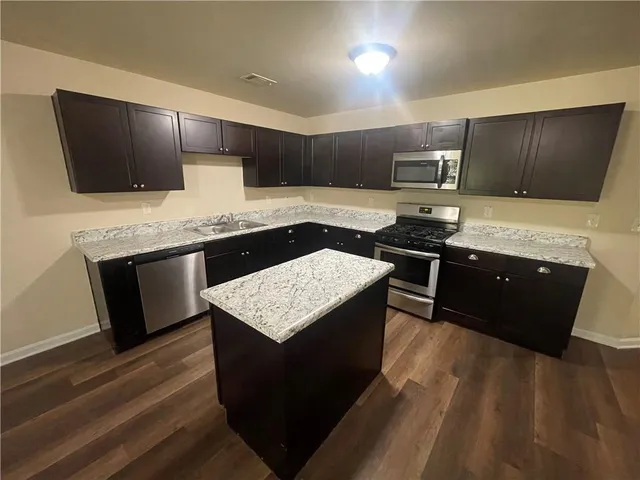 a kitchen with stainless steel appliances kitchen island granite countertop a stove a sink and a microwave