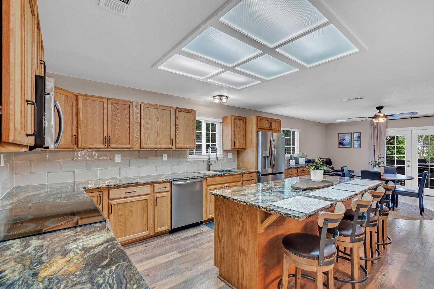 12354 Hobday Road Wilton, CA 95693 - Photo 42 of 77 kitchen featuring dark stone counters, a center island, light wood-style floors, and tasteful backsplash