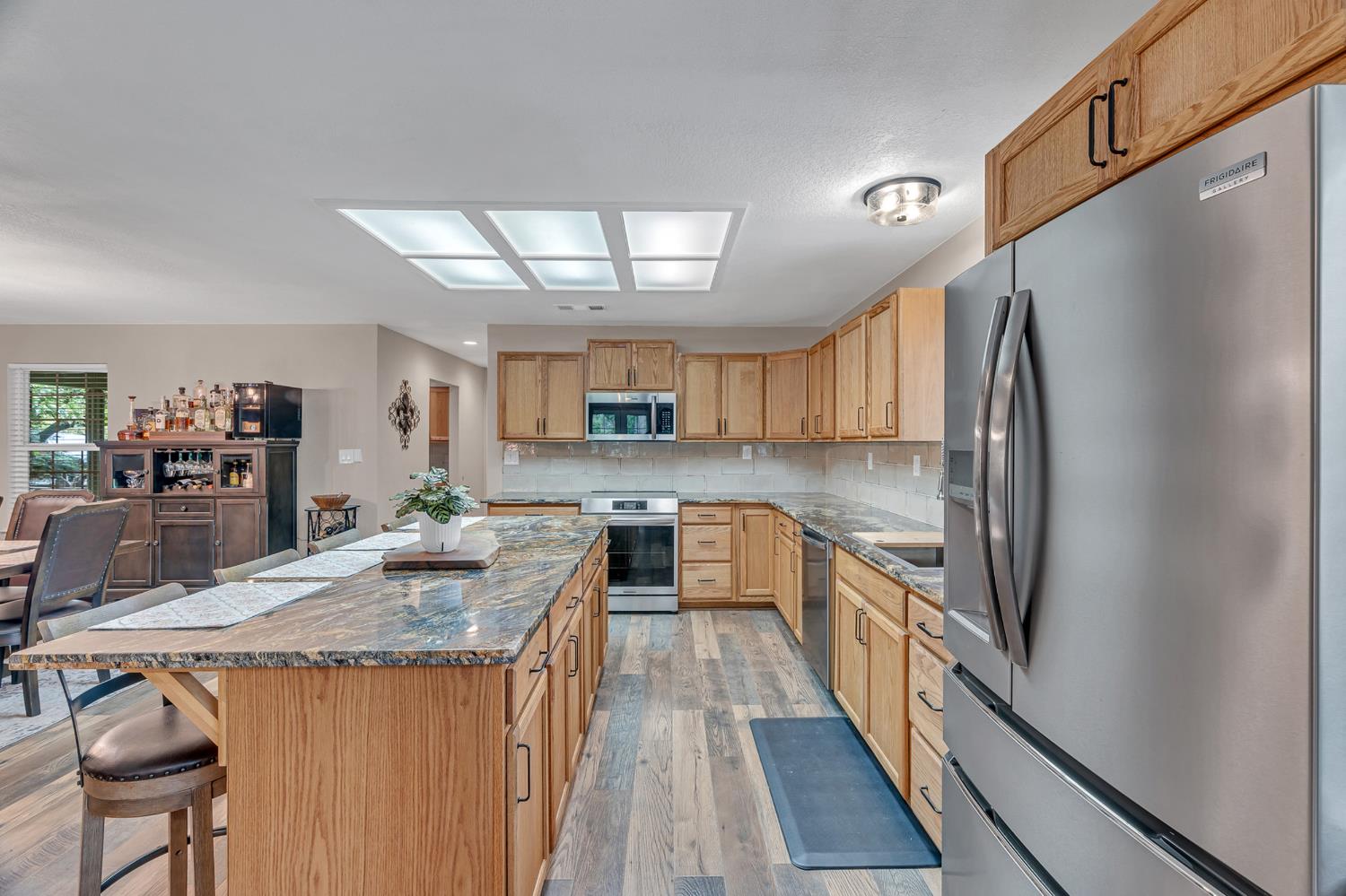 12354 Hobday Road Wilton, CA 95693 - Photo 47 of 77 kitchen featuring dark stone countertops, stainless steel appliances, a kitchen bar, a center island, and light wood-style floors