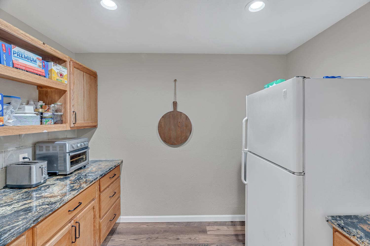 12354 Hobday Road Wilton, CA 95693 - Photo 50 of 77 Pantry with freestanding refrigerator, dark stone counters, open shelves, dark wood finished floors, and recessed lighting
