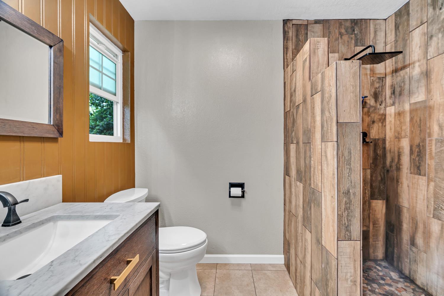 12354 Hobday Road Wilton, CA 95693 - Photo 61 of 77 full bathroom with vanity, a walk in shower, light tile patterned floors, and wood walls