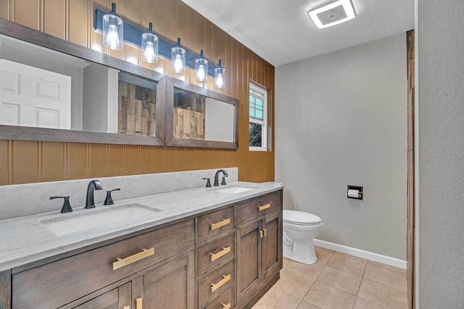 12354 Hobday Road Wilton, CA 95693 - Photo 62 of 77 full bathroom featuring double vanity, wood walls, and light tile patterned flooring
