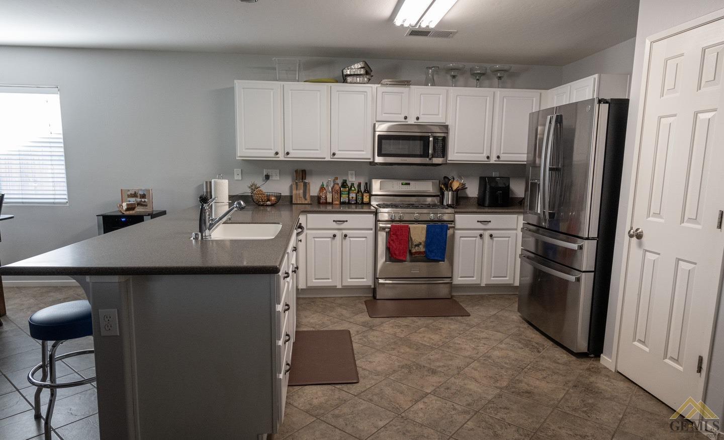 Undisclosed Address Bakersfield, CA 93312 - Photo 5 of 21 a kitchen with stainless steel appliances a stove refrigerator sink and microwave