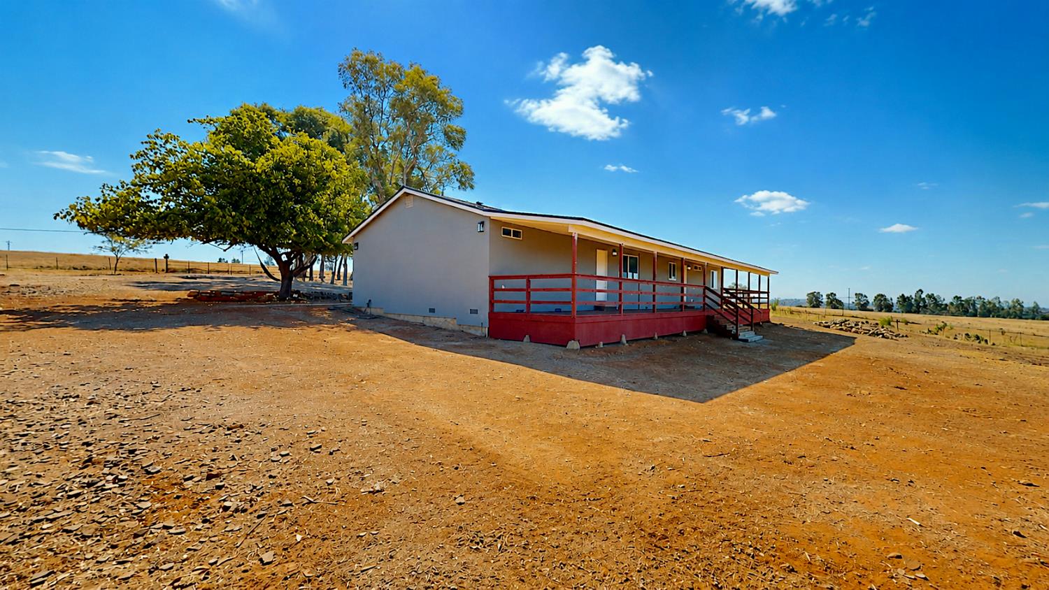 4728 Zorro Road La Grange, CA 95329 - Photo 7 of 56 Single-story residence with a covered back porch featuring a red railing, set on a broad, open lot with natural terrain