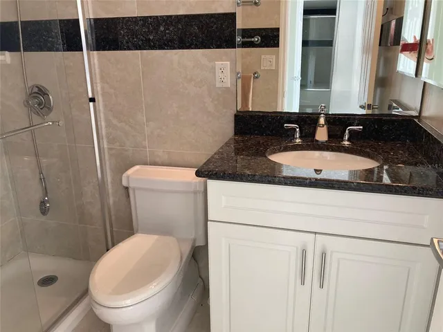 a bathroom with a granite countertop sink a toilet and bathtub