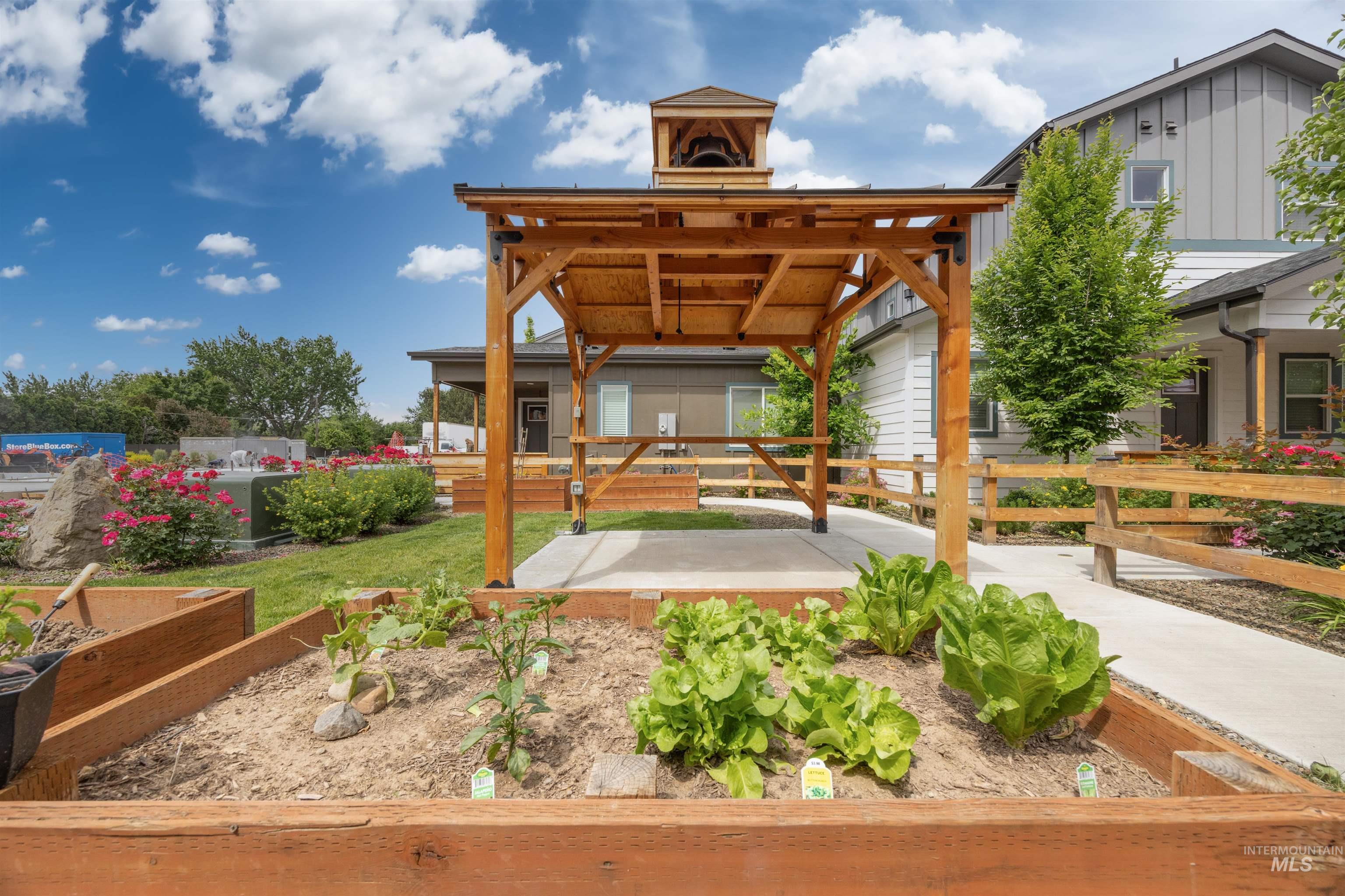 1408 North Cole Road Boise, ID 83704 - Photo 30 of 32 Community garden area featuring raised planter beds, a wood pergola structure, paved walkways, and natural wood fencing