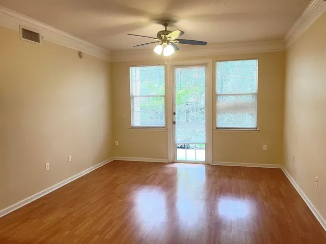 a view of an empty room with wooden floor and a window