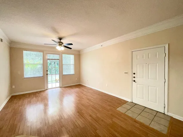 a view of an empty room with a window and wooden floor