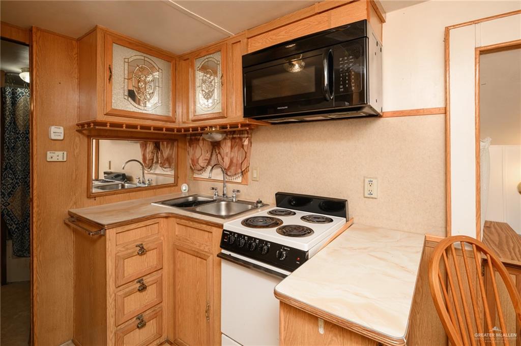 215 South Valley View Road, Unit 227 Donna, TX 78537 - Photo 7 of 18 a kitchen with a stove a microwave and cabinets