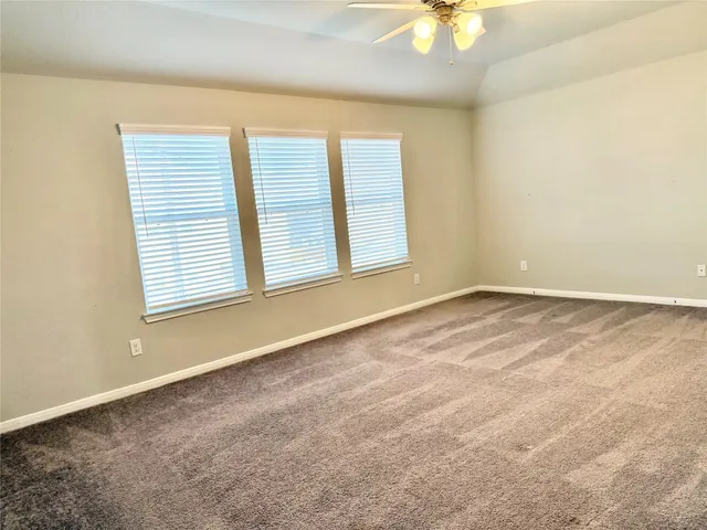 an empty room with a window and a chandelier fan