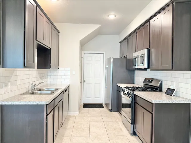 a kitchen with stainless steel appliances granite countertop a sink stove and refrigerator