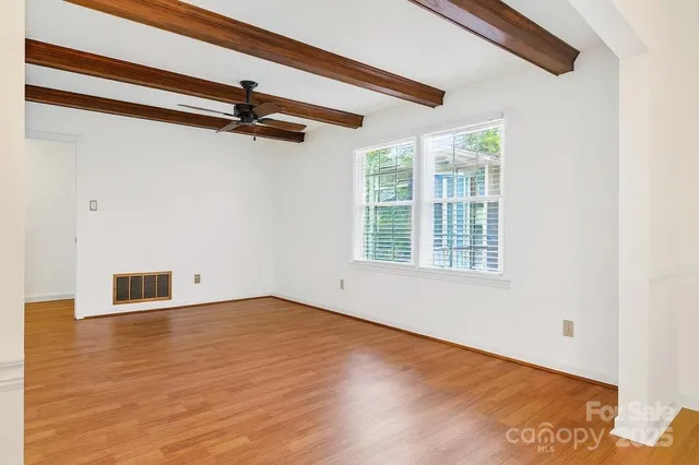 a view of an empty room with a window and wooden floor