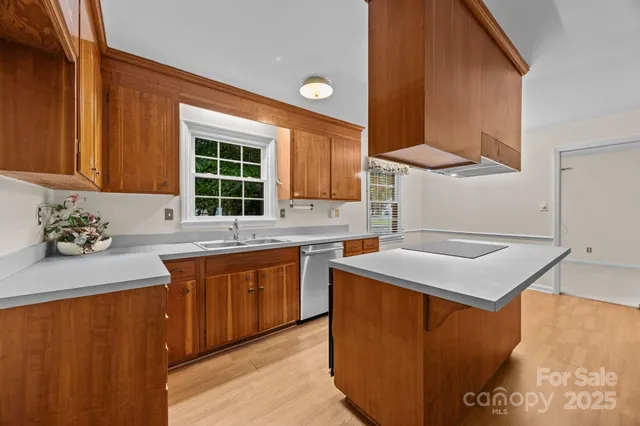 a kitchen with stainless steel appliances granite countertop a sink dishwasher stove and a refrigerator with wooden cabinets