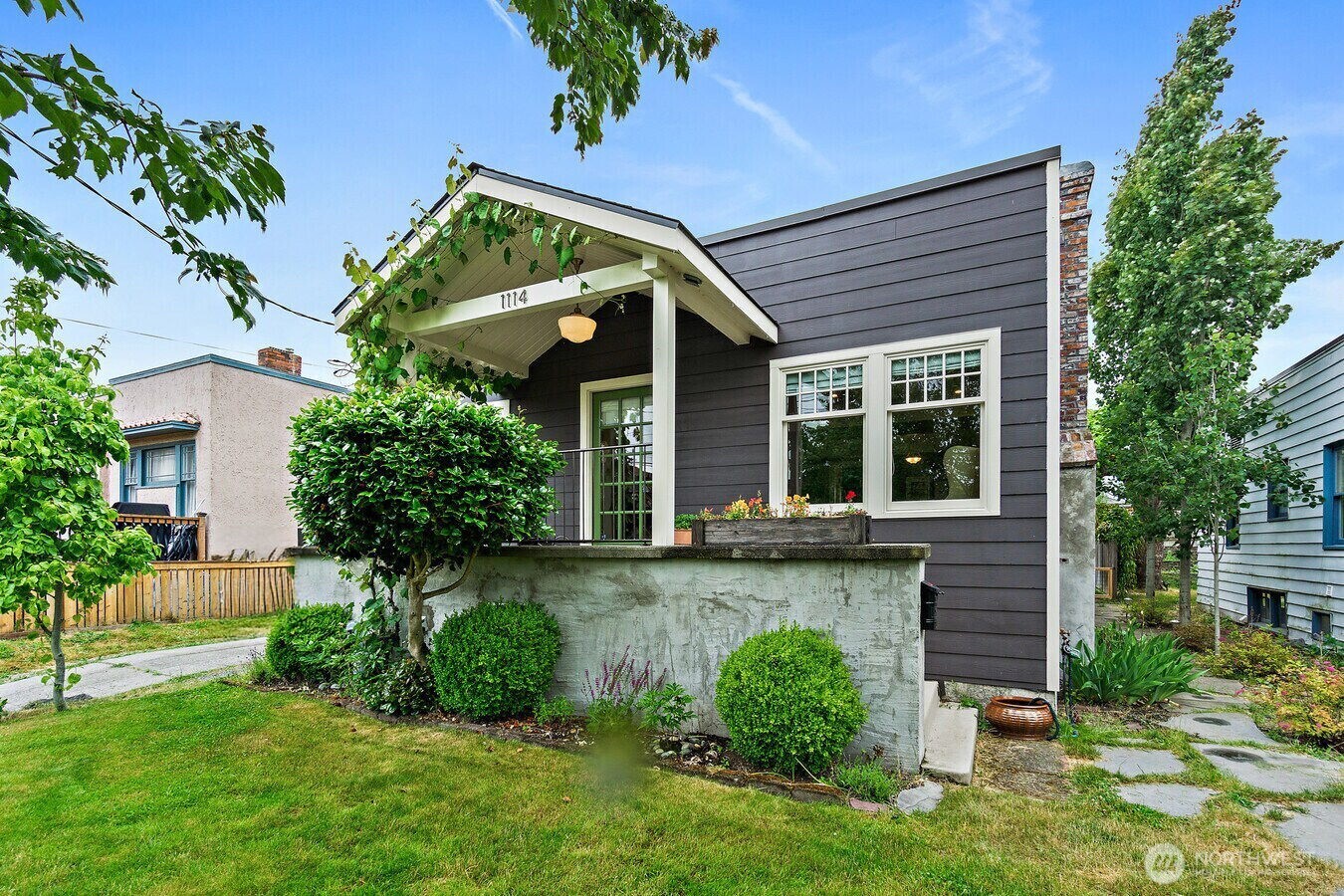 a front view of a house with a yard and potted plants