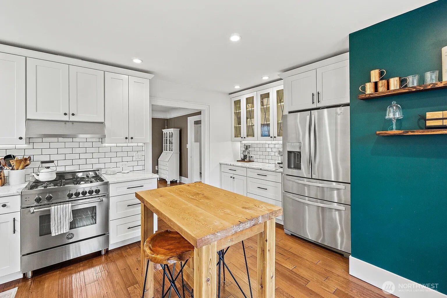 1114 North 77th Street Seattle, WA 98103 - Photo 13 of 30 a kitchen with stainless steel appliances a stove a refrigerator and white cabinets with wooden floors