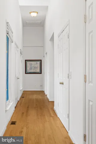 a view of a hallway with wooden floor and a bathroom