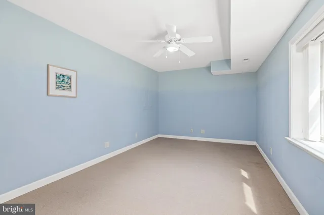 an empty room with a window and a fan