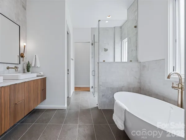 a bathroom with a tub a sink a mirror and a shower