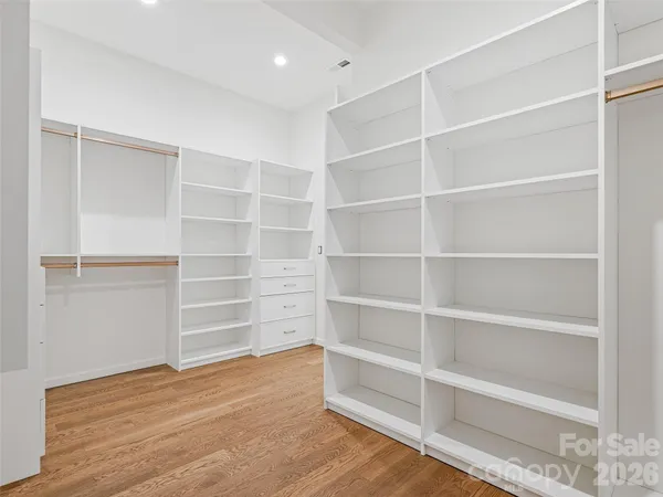 a view of an empty room with wooden floor and closet