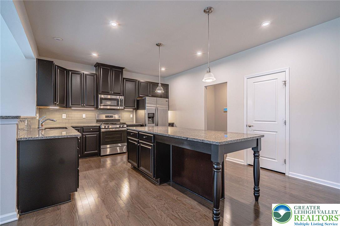2584 Raya Way Easton, PA 18045 - Photo 12 of 50 a kitchen with stainless steel appliances granite countertop a stove top oven a sink dishwasher a dining table and chairs with wooden floor
