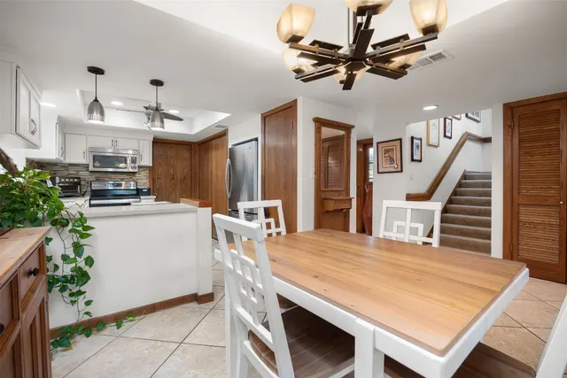 a kitchen with stainless steel appliances kitchen island a table chairs in it and floors