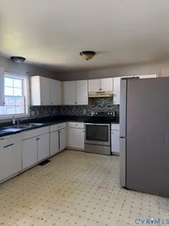 a kitchen with granite countertop a refrigerator and cabinets