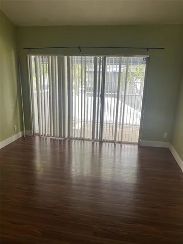 a view of empty room with wooden floor and floor to ceiling window