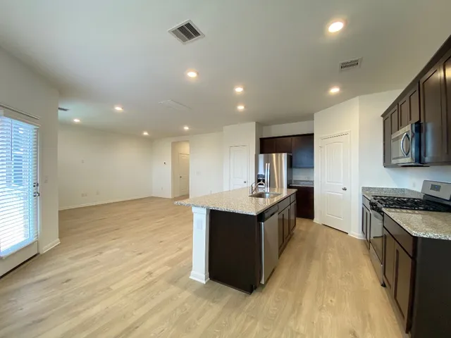 a large kitchen with stainless steel appliances granite countertop a large counter top and wooden floors