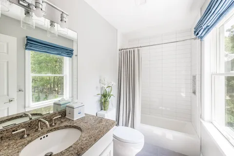 a bathroom with a granite countertop sink toilet and shower