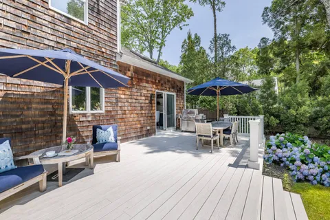 a view of a patio with wooden chairs and a table