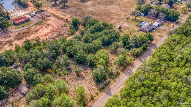 an aerial view of residential house with outdoor space and trees all around
