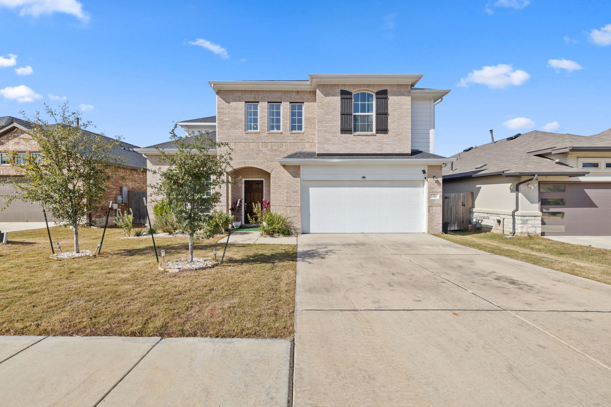Traditional home featuring driveway, a front yard, a garage, and brick siding