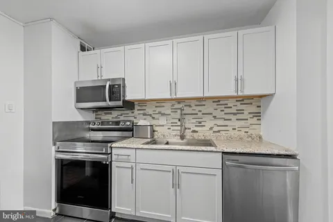 a kitchen with granite countertop white cabinets and stainless steel appliances