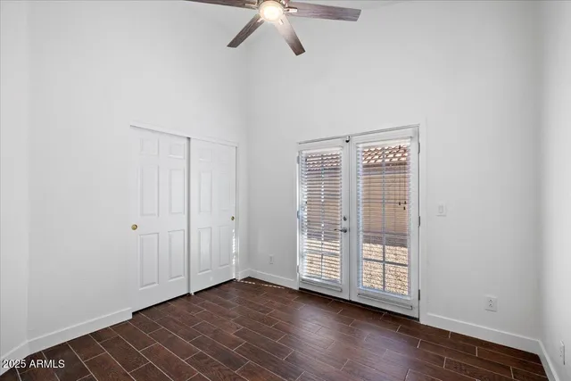 an empty room with wooden floor fan and windows