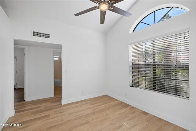 a view of an empty room with a window and wooden floor