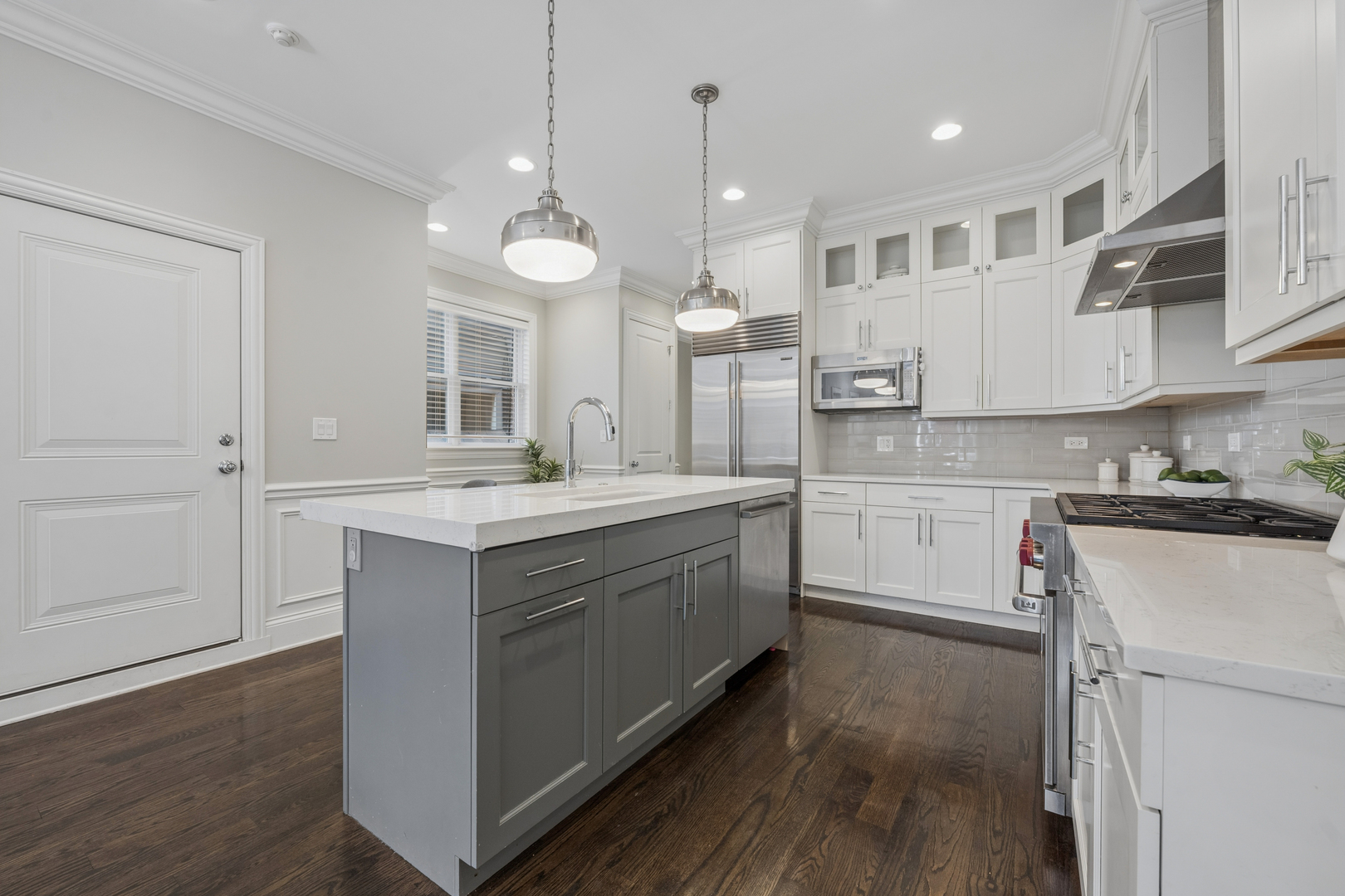 2740 North Seminary Avenue, Unit 1 Chicago, IL 60614 - Photo 20 of 46 a large white kitchen with a large kitchen island white cabinets and wooden floor