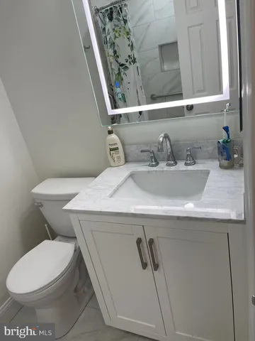 a bathroom with a granite countertop toilet sink and mirror