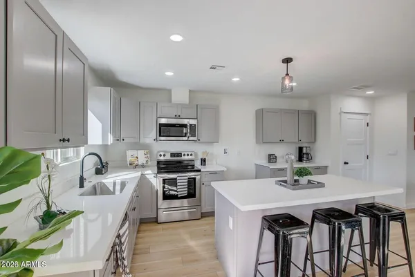 a kitchen with stainless steel appliances granite countertop a sink a stove a refrigerator cabinets and chairs