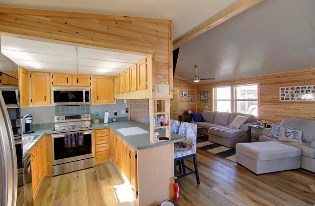 a living room with stainless steel appliances furniture and a kitchen view
