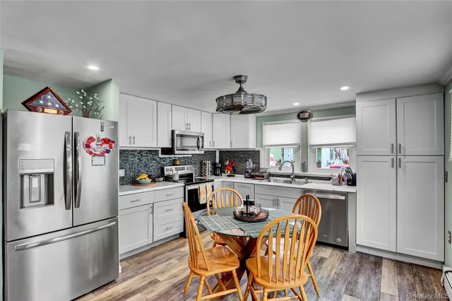 a kitchen with kitchen island white cabinets and stainless steel appliances