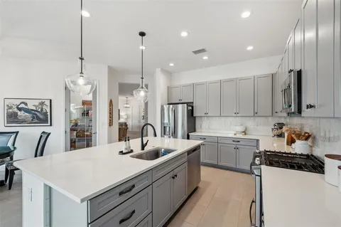 a kitchen with kitchen island granite countertop a sink a counter space appliances and cabinets