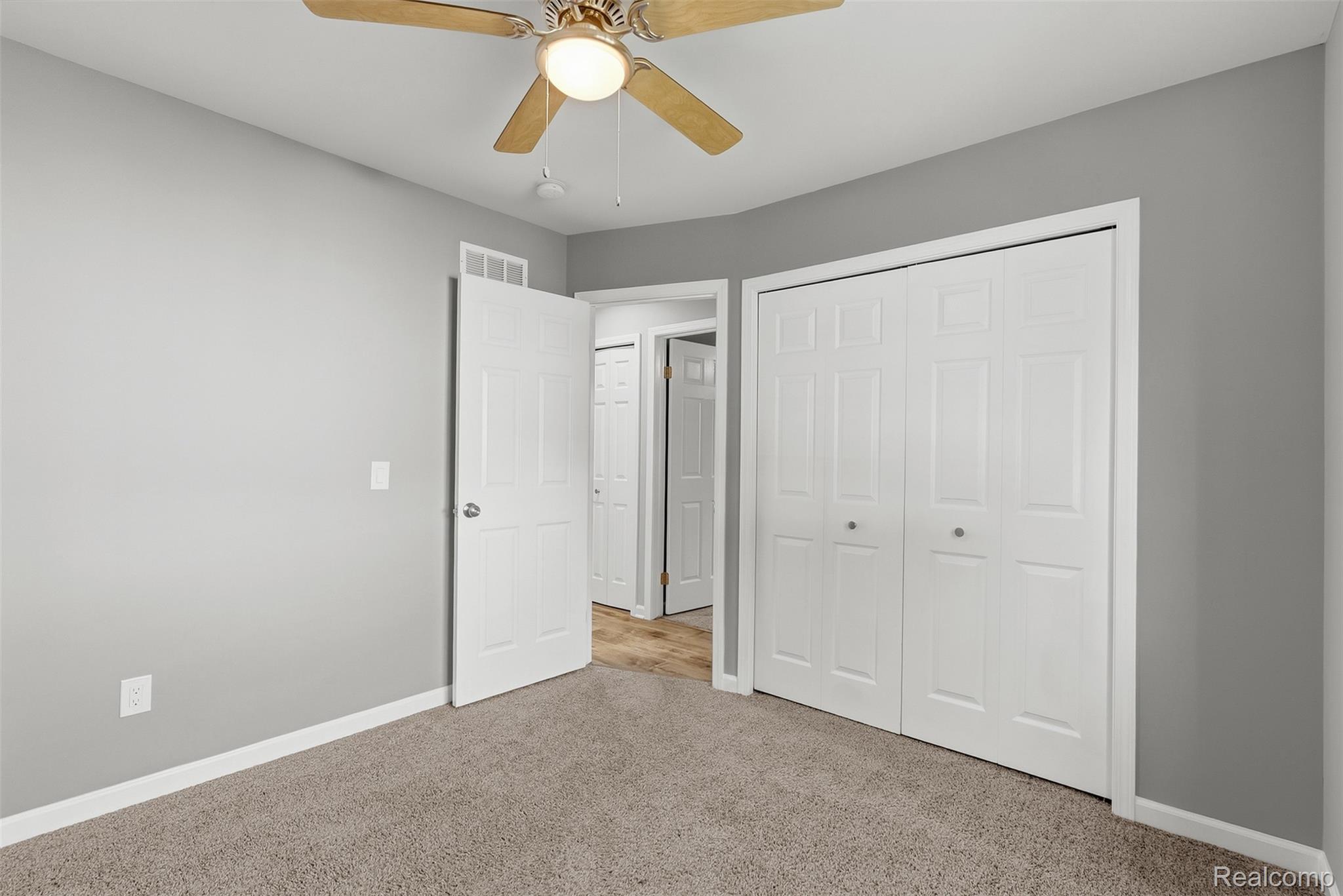 1750 Henbert Road West Bloomfield, MI 48324 - Photo 21 of 32 Textured carpeting, neutral wall paint, white trim, bi-fold closet doors, and a ceiling fan with integrated lighting