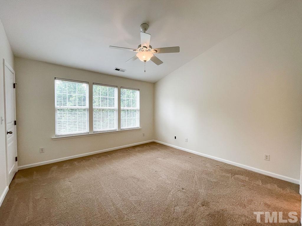 7841 Silverthread Lane Raleigh, NC 27617 - Photo 7 of 15 an empty room with chandelier fan and windows