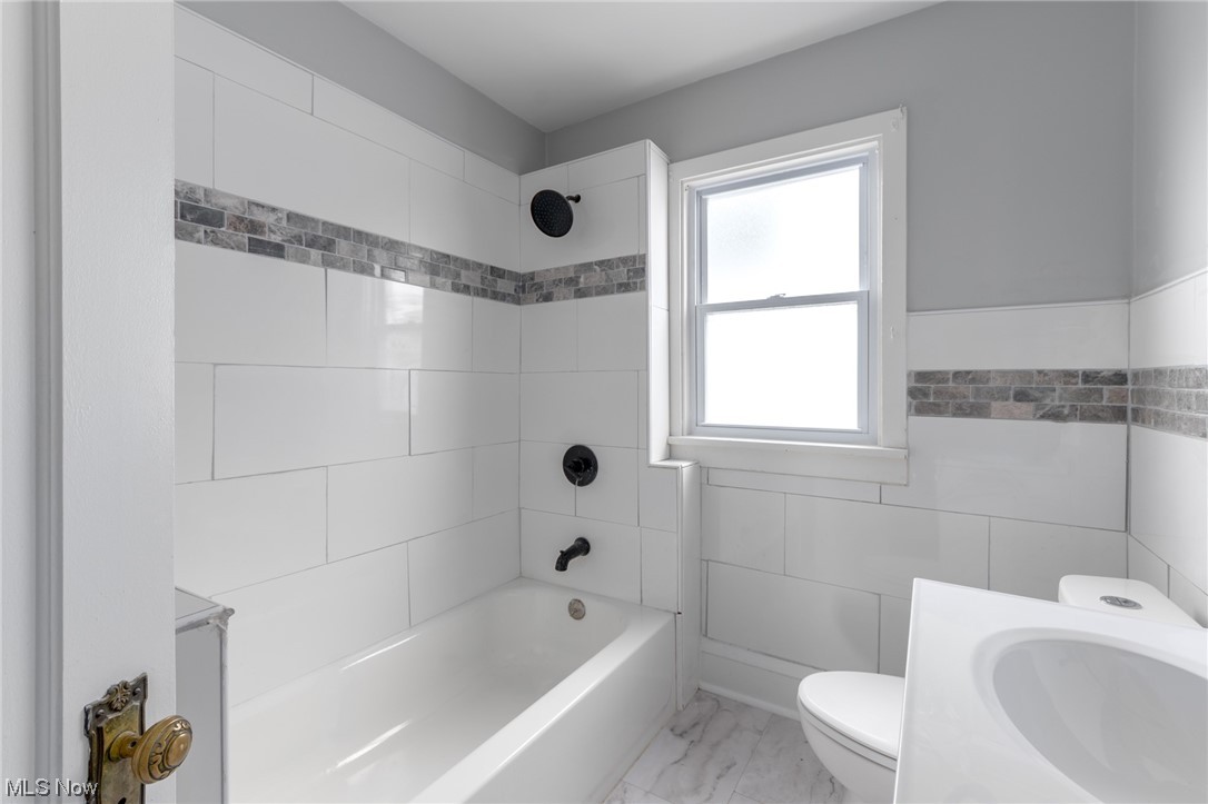1228 Melbourne Road Cleveland, OH 44112 - Photo 14 of 35 Full bathroom featuring toilet, tile walls, tile flooring, tiled shower / bath, and vanity