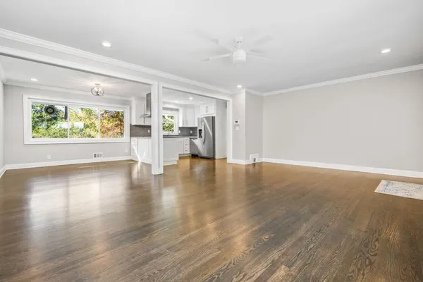 a view of an empty room with wooden floor and a window